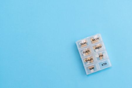 Pill organizer with variety of pills and supplement. Weekly Pill container on blue background with copy spaceの写真素材