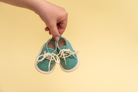 Female hand holding tiny baby shoes. Newborn concept.の写真素材