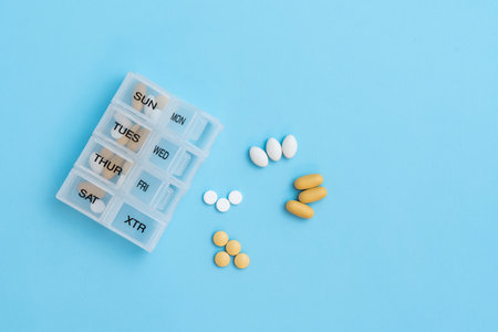 Top view of pill organizer with variety of pills and supplement. Weekly Pill container on blue background with copy spaceの写真素材