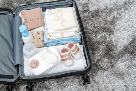Top view of bag for maternity hospital. Suitcase of baby clothes prepared for newborn birth. Concept...