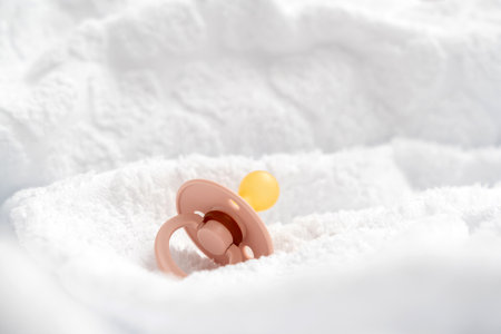 Baby pink pacifier on the background of a white terry towelの写真素材