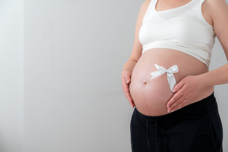 Pregnant female tummy with a white bow as a concept of the joys of childbirthの写真素材