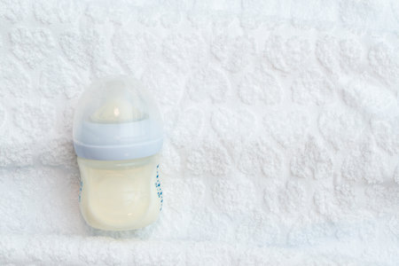 A half-empty bottle of milk nutrition lies on a white towel with copy spaceの写真素材