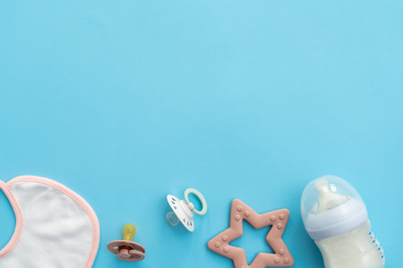 Baby essentials spread on tranquil blue, top view with expansive space for text