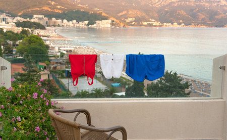 Swimsuits drying on the balcony of a modern hotel overlooking the coastの写真素材