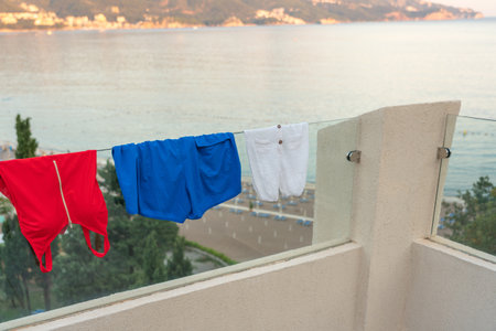 Swimsuits drying on the glass railing of a modern hotel balcony as a national flag conceptの写真素材