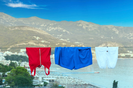 Swimsuits drying on the glass railing of the balcony of a modern hotel against the blue skyの写真素材
