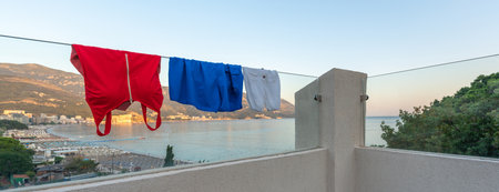 Swimsuits dry on the glass railing of a modern balcony in the colors of the flags of Russia and Serbiaの写真素材