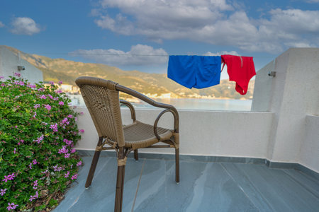 A pair of drying swimsuits overlooking the beautiful coastline from the balcony of a modern hotelの写真素材
