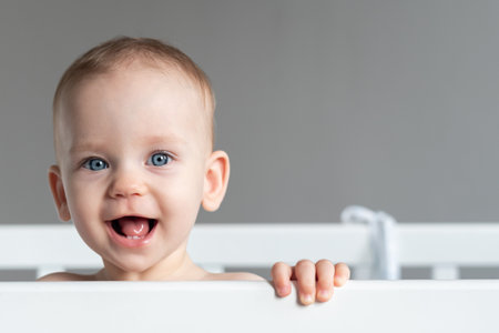One year old baby standing in a crib smilingの写真素材