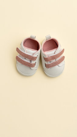 Baby pink shoes on yellow paper background with copy space. Baby clothes concept. Top view, flat layの写真素材