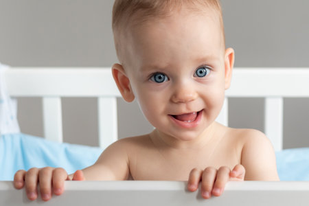 One year old baby standing in a crib smilingの写真素材