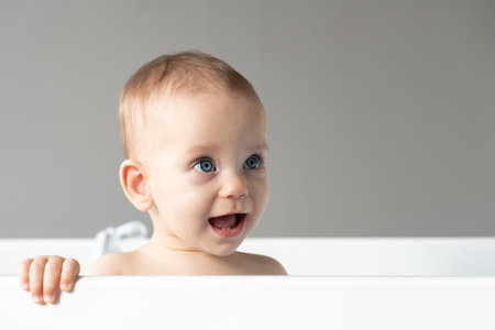 The naive look of a baby with an open mouth as an expression of the first happy emotionsの写真素材