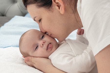 mother hugs her newborn and cuddles her cheekの写真素材