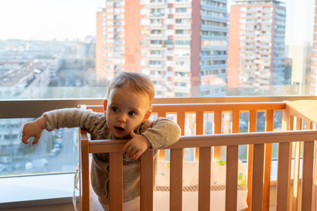 the baby looks interestedly inside the room, not paying attention to the landscape outside the windowの写真素材