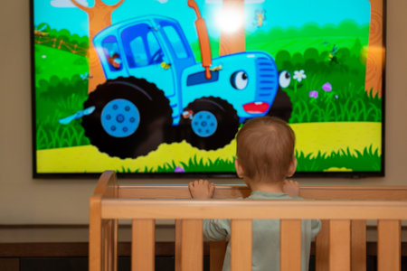 Large screen with cartoons. The baby looks in fascinationの写真素材