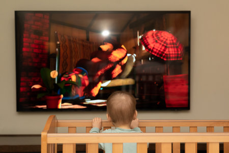 Bright cartoons fascinate a small child when he looks at the screenの写真素材