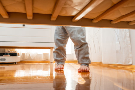 Baby standing firmly barefoot in a crib photographed from the floor. Hidden frame conceptの写真素材