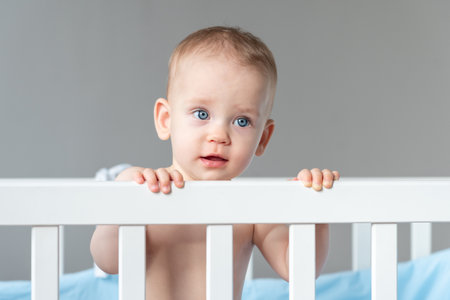 The baby pulls himself up on the back of the crib with little effortの写真素材