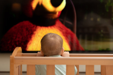 The babys cute head is barely visible from the crib. Watching cartoons on TVの写真素材