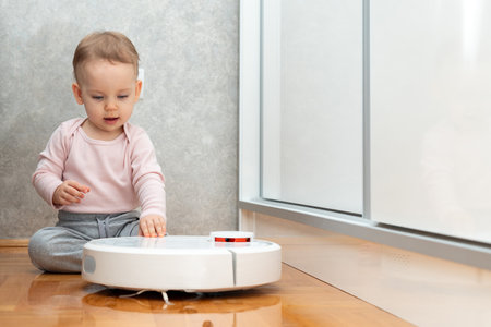 The baby carefully feels the robot vacuum cleaner. The concept of learning about surrounding objectsの写真素材