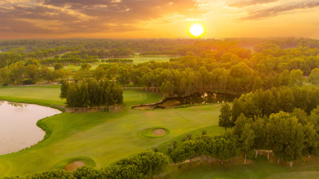 Panorama of amazing golf course at sunset with dramatic sky. Scenic panoramic view of golf fairway with pond. Golf field with beautiful pinesの写真素材