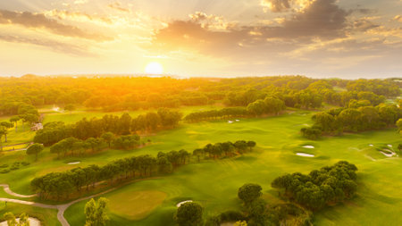 Golf course at sunset with beautiful sky and sand trap. Scenic panoramic view of golf fairway with bunker. Golf field with pinesの写真素材