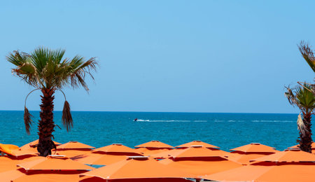 The serene surface of the sea above the roofs of bright orange sun umbrellasの写真素材