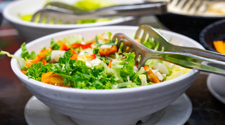 Special tongs in a salad of tomatoes, bell peppers and green lettuce leaves. Healthy eating conceptの写真素材
