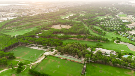 Golf course at sunset with beautiful sky and sand trap. Scenic panoramic view of golf fairway with bunker. Golf field with pinesの写真素材