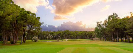 A picturesque golf course with lush greenery, a tranquil pond, and a warm sunset sky, offering a serene outdoor retreat.の写真素材