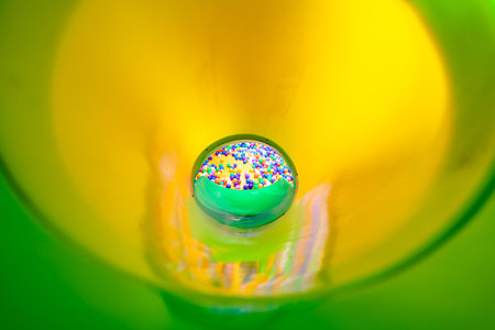 A dynamic view inside a bright green slide leading to a colorful ball pit.の写真素材