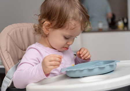 A toddler sitting in a highchair exploring their meal in a calm home environment.の写真素材