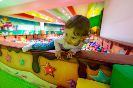 A playful child climbing over a colorful wall in a vibrant indoor playground.の写真素材