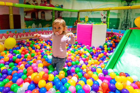 A happy child enjoying a colorful ball pit in a vibrant indoor playground full of fun.の写真素材