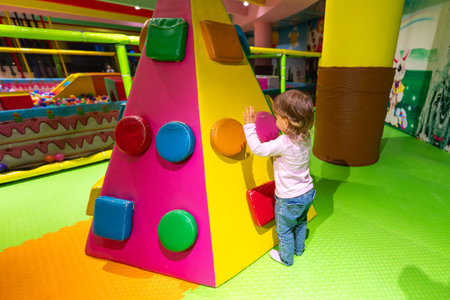 A child exploring a colorful soft climbing wall in a vibrant indoor playground.の写真素材