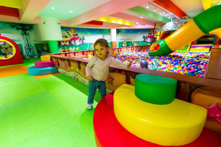 A happy child exploring a colorful indoor playground with soft structures and a ball pit.の写真素材