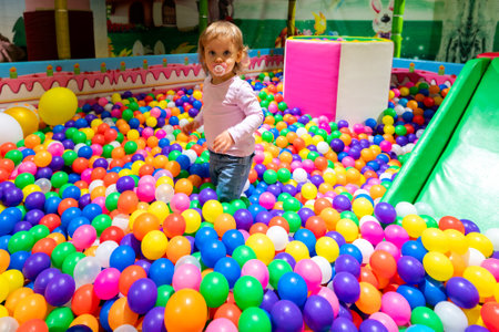 A cheerful child having fun in a colorful ball pit at a lively indoor playground.の写真素材