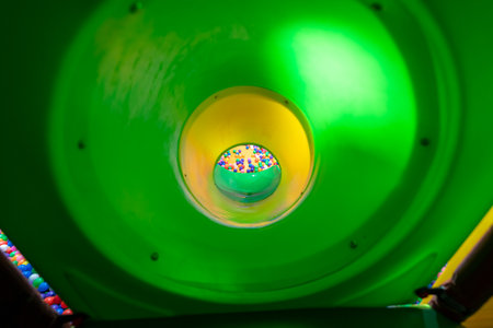 A thrilling perspective from inside a green tunnel slide leading to a vibrant ball pit.の写真素材