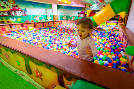 A joyful child exploring a vibrant indoor playground with a colorful ball pit.の写真素材