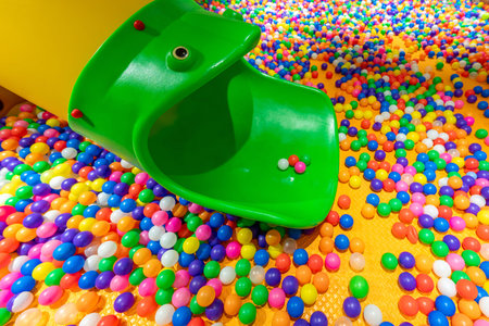 A fun green slide leading into a vibrant ball pit filled with colorful plastic balls.