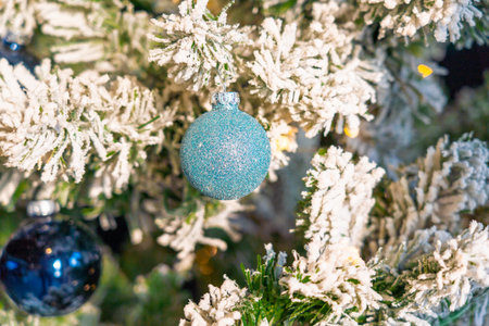 Close-up of a frosted Christmas tree decorated with blue sparkling ornaments.の写真素材