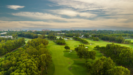 A panoramic view of a golf course with lush greenery and a cloudy skyの写真素材