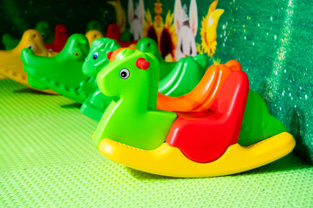 Bright plastic rocking horses in a cheerful indoor play area for kids.の写真素材