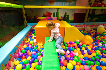 A child exploring soft play structures in a colorful ball pit at a vibrant indoor playground.の写真素材