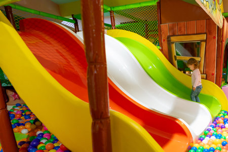 A cheerful child climbing towards a colorful triple slide in a lively indoor playground.の写真素材