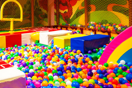 Colorful indoor ball pit with soft obstacles and a rainbow slide for kids.の写真素材