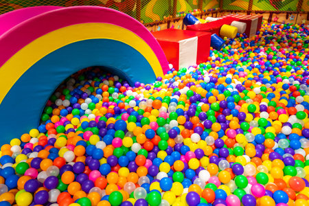 A colorful ball pit with a rainbow-shaped soft structure in a vibrant indoor playground.の写真素材