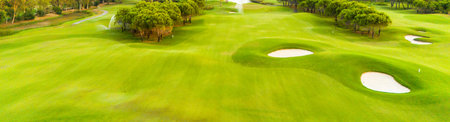 A panoramic view of a golf course with sand traps and vibrant greeneryの写真素材