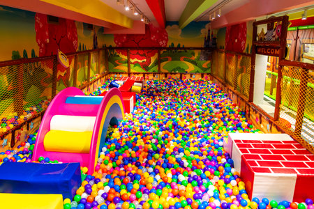 Spacious indoor play area with a vibrant rainbow slide and ball pit for kids.の写真素材